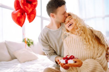 Evde Sevgililer Günü 'nü kutlayan güzel genç bir çift. Sevgililer birbirlerine hediyeler verir. Sarıl, öp ve birlikte vakit geçirmekten zevk al..