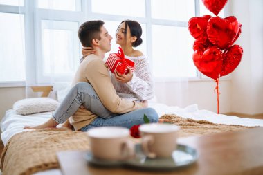 Sevgililer Günü konsepti. Sevgililer birbirlerine hediyeler verir. Evde Sevgililer Günü 'nü kutlayan genç bir çift..