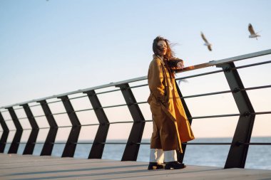 İskelede genç bir kadın. Güzel bir kadın deniz sahilinde martıları besler. Özgürlük, seyahat, uçma kavramı. Yaşam tarzı anı.