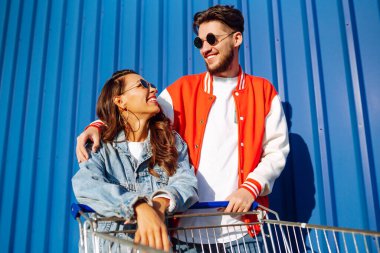 Şık bir erkek ve kadın eğleniyor ve alışveriş arabasına biniyor. Yaşam tarzı, eğlence, eğlence, gençlik kavramı.