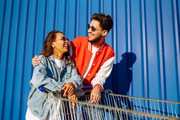Şık bir erkek ve kadın eğleniyor ve alışveriş arabasına biniyor. Yaşam tarzı, eğlence, eğlence, gençlik kavramı.