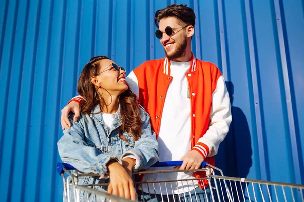 Şık bir erkek ve kadın eğleniyor ve alışveriş arabasına biniyor. Yaşam tarzı, eğlence, eğlence, gençlik kavramı.
