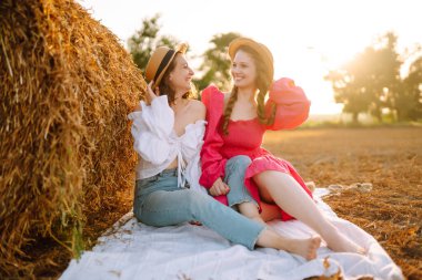 Two young women posing near haystack. Fashion concept. Nature, vacation, relax and lifestyle. Summer concept.