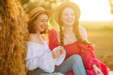 Samanlığın yanında poz veren iki genç kadın. Moda konsepti. Doğa, tatil, rahatlama ve yaşam tarzı. Yaz konsepti.