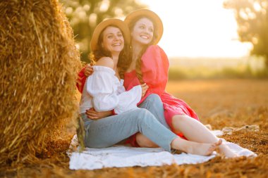 Samanlığın yanında poz veren iki genç kadın. Moda konsepti. Doğa, tatil, rahatlama ve yaşam tarzı. Yaz konsepti.