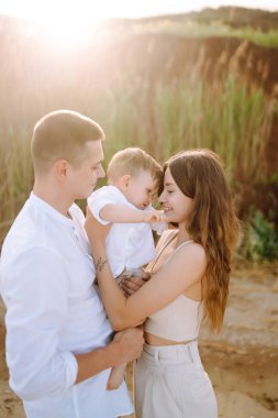 Baba, anne ve çocuk sahilde dinleniyor. Genç aile yaz tatilinde eğleniyor. Seyahat, doğa, aktif yaşam tarzı, tatil köyü kavramı.