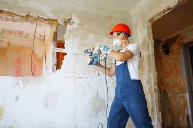 Repairer in boilersuit holding tools. Apartment repair and renovation concept.