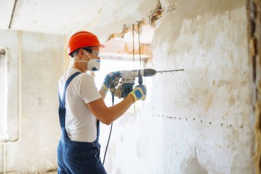Repairer in boilersuit holding tools. Apartment repair and renovation concept.