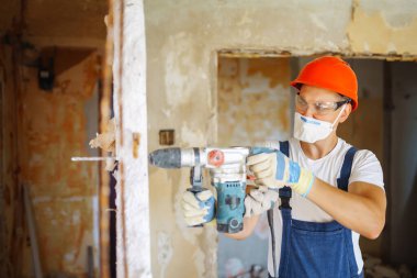 Repairer in boilersuit holding tools. Apartment repair and renovation concept.
