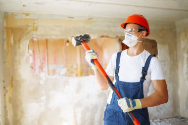 Repairer in boilersuit holding tools. Apartment repair and renovation concept.