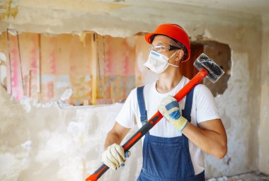 Repairer in boilersuit holding tools. Apartment repair and renovation concept.