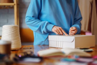 Masaya bir paket hazırlıyorum. Nline mağazası, küçük işletme sahibi, satıcı, girişimci, paketleme çantası, posta kutusu, masada bir paket hazırlamak. E-ticarette sevkiyat dağıtımı kavramı.
