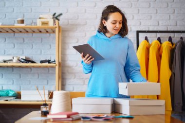 Küçük işletme sahibi, girişimci, ecommerce giyim mağazasının siparişlerini kontrol eden tablet satıcı. Çevrimiçi satış.