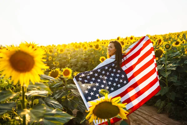 Ung Kvinna Håller Stolt Den Amerikanska Flaggan Solrosfältet Patriot Hissar — Stockfoto