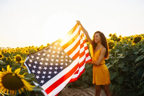 Ung Kvinna Håller Stolt Den Amerikanska Flaggan Solrosfältet Patriot Hissar — Stockfoto