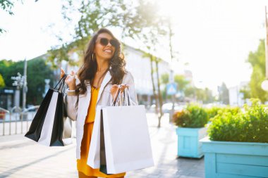 Alışveriş torbalarıyla sokakta yürüyen şık bir kadın. Tüketim, satış, alım, alışveriş, yaşam tarzı konsepti.