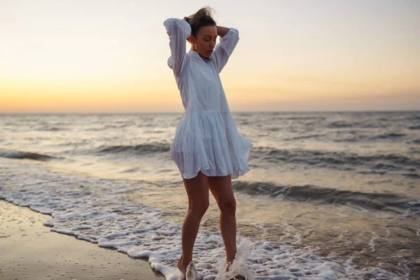 身穿白色飘扬衣服的年轻而快乐的女人沿着海滨散步 女孩看着神奇的日出 放松和生活方式概念 — 图库照片