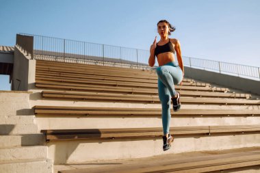 Spor kıyafetli genç bir kadın sabahları dışarıda egzersiz yapıyor. Spor kadını esneme egzersizi yapıyor. Spor, aktif yaşam, spor eğitimi, sağlıklı yaşam tarzı..