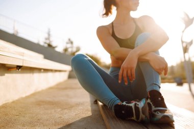 Spor kıyafetli genç bir kadın sabahları dışarıda egzersiz yapıyor. Spor kadını esneme egzersizi yapıyor. Spor, aktif yaşam, spor eğitimi, sağlıklı yaşam tarzı..