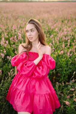 Çiçek açan alanda mutlu bir kadın. Doğa, tatil, rahatlama ve yaşam tarzı. Yaz manzarası. Moda, tarz kavramı.