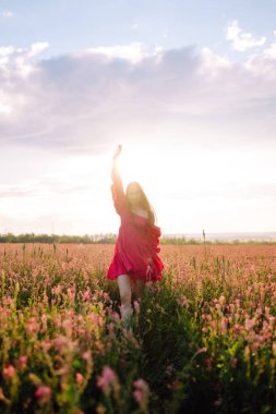 Çiçek açan alanda mutlu bir kadın. Doğa, tatil, rahatlama ve yaşam tarzı. Yaz manzarası. Moda, tarz kavramı.