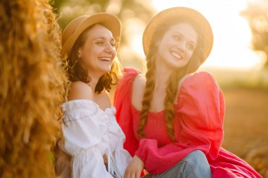 Samanlığın yanında eğlenen iki genç kadın. Moda konsepti. Doğa, tatil, rahatlama ve yaşam tarzı. Güzel rakamlar. Süper ruh hali. Yaz konsepti.