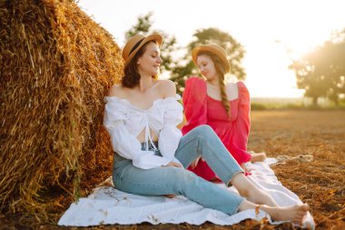 Samanlığın yanında eğlenen iki genç kadın. Moda konsepti. Doğa, tatil, rahatlama ve yaşam tarzı. Güzel rakamlar. Süper ruh hali. Yaz konsepti.