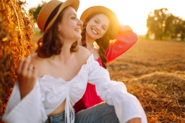 Samanlığın yanında eğlenen iki genç kadın. Moda konsepti. Doğa, tatil, rahatlama ve yaşam tarzı. Güzel rakamlar. Süper ruh hali. Yaz konsepti.