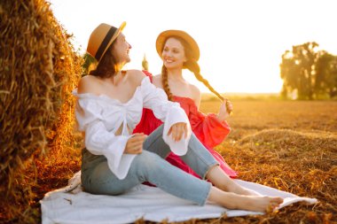 Samanlığın yanında eğlenen iki genç kadın. Moda konsepti. Doğa, tatil, rahatlama ve yaşam tarzı. Güzel rakamlar. Süper ruh hali. Yaz konsepti.
