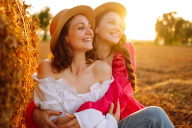 Samanlığın yanında eğlenen iki genç kadın. Moda konsepti. Doğa, tatil, rahatlama ve yaşam tarzı. Güzel rakamlar. Süper ruh hali. Yaz konsepti.