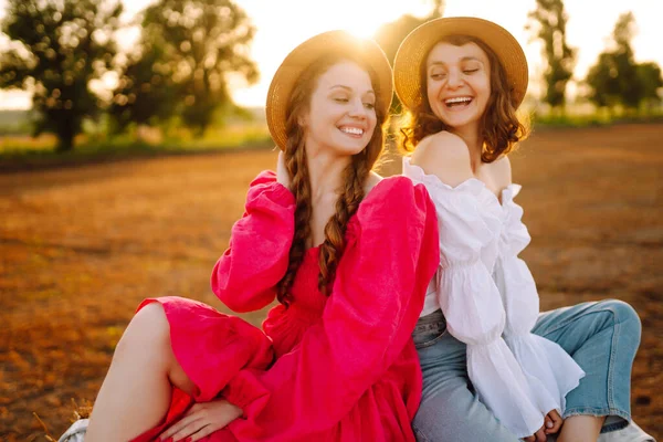 Samanlığın yanında eğlenen iki genç kadın. Moda konsepti. Doğa, tatil, rahatlama ve yaşam tarzı. Güzel rakamlar. Süper ruh hali. Yaz konsepti.