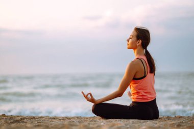 Genç ve güzel bir kadın yoga yapıyor ve sahilde meditasyon yapıyor. Spor, Aktif Yaşam. 