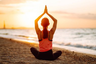 Genç ve güzel bir kadın yoga yapıyor ve sahilde meditasyon yapıyor. Spor, Aktif Yaşam. 