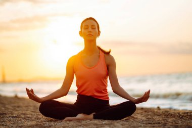 Genç ve güzel bir kadın yoga yapıyor ve sahilde meditasyon yapıyor. Spor, Aktif Yaşam. 