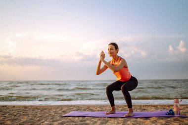 Spor giyimli genç bir kadın yoga yapıyor, plajda spor egzersizi yapıyor. Spor, Aktif Yaşam. 