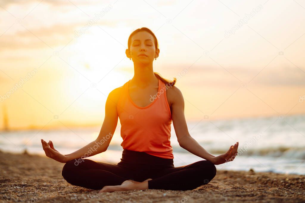 Young beautiful woman practices yoga and meditates on the beach. Sport, Active life. 