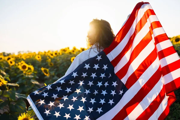 美丽的女孩在向日葵田里 戴着美国国旗 7月4日7月4日自由 夕阳灯 女孩微笑 美丽的日落 独立日爱国假期 — 图库照片