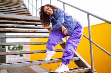 Şık giyinmiş, dans eden ve birkaç hareket gösteren bir sokak dansçısı. Spor, dans ve şehir kültürü konsepti.