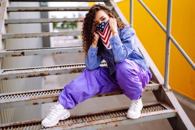 Amerikan bandanalı şık elbiseli bir sokak dansçısı dans ediyor ve birkaç hareket sergiliyor. Spor, dans ve şehir kültürü konsepti.