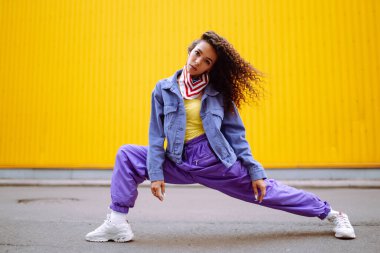 Şık giyinmiş, dans eden ve birkaç hareket gösteren bir sokak dansçısı. Spor, dans ve şehir kültürü konsepti.