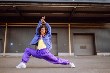 Şık giyinmiş, dans eden ve birkaç hareket gösteren bir sokak dansçısı. Spor, dans ve şehir kültürü konsepti.