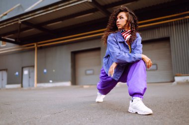 Şık giyinmiş, dans eden ve birkaç hareket gösteren bir sokak dansçısı. Spor, dans ve şehir kültürü konsepti.