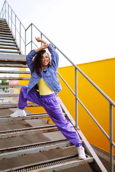 Şık giyinmiş, dans eden ve birkaç hareket gösteren bir sokak dansçısı. Spor, dans ve şehir kültürü konsepti.