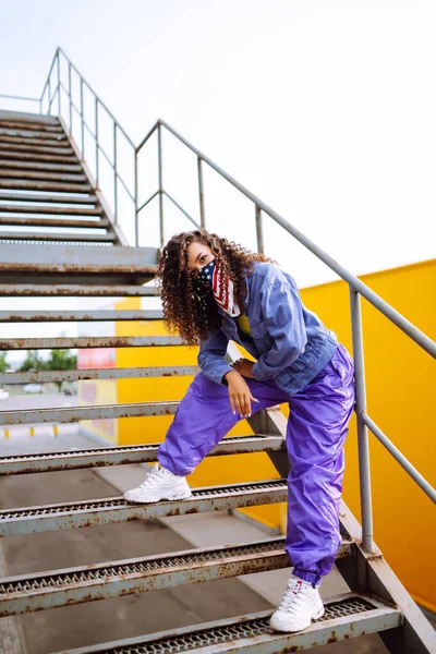 Amerikan bandanalı şık elbiseli bir sokak dansçısı dans ediyor ve birkaç hareket sergiliyor. Spor, dans ve şehir kültürü konsepti.