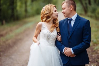 Gelin ve damat parkta birlikte yürürler. Mutlu düğün çifti eğleniyor. Düğün günü. Evlilik..