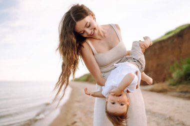 Güzel anne ve çocuk sahilde dinleniyor. Seyahat, doğa, aktif yaşam tarzı, tatil köyü konsepti. Mutlu çocukluk. 