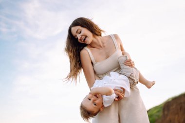 Güzel anne ve çocuk sahilde dinleniyor. Seyahat, doğa, aktif yaşam tarzı, tatil köyü konsepti. Mutlu çocukluk. 