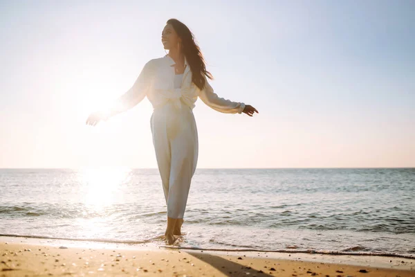 若い女性が海岸沿いを歩いている 少女は不思議な日の出を見る リラックスしてライフスタイルのコンセプト — ストック写真