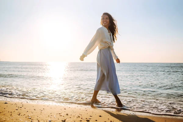 年轻的女人沿着海滨散步 女孩看着神奇的日出 放松和生活方式概念 — 图库照片