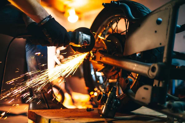 The hands of the master  with a grinder. metal works in the workshop close up. Sparks in metalworking.